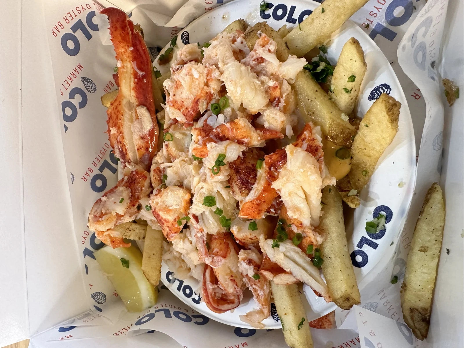 takeout tray of lobster meat piled over garlic fries w/ scallions + lemon at Cousins Ma…