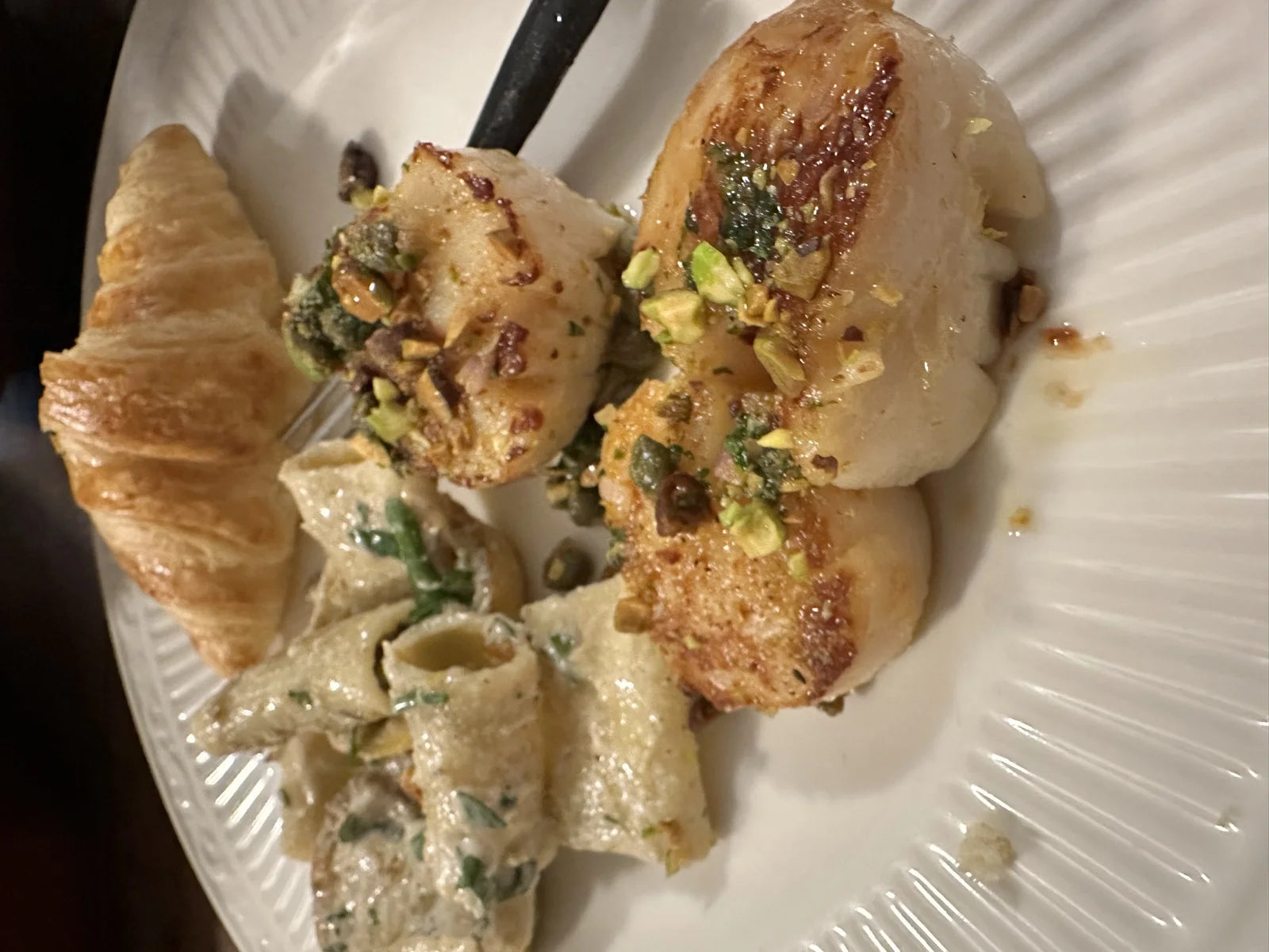 plate of seared pistachio-crusted scallops w/ creamy paccheri pasta and a golden croissant