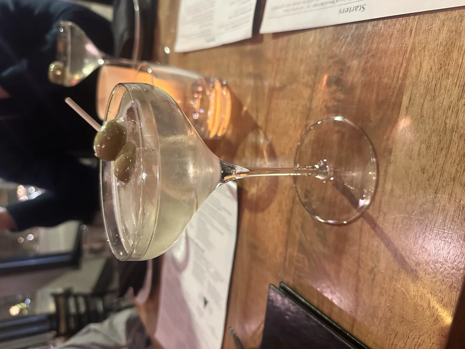 dirty martini w/ blue-cheese-stuffed olives on a pick in a coupe glass at a restaurant …