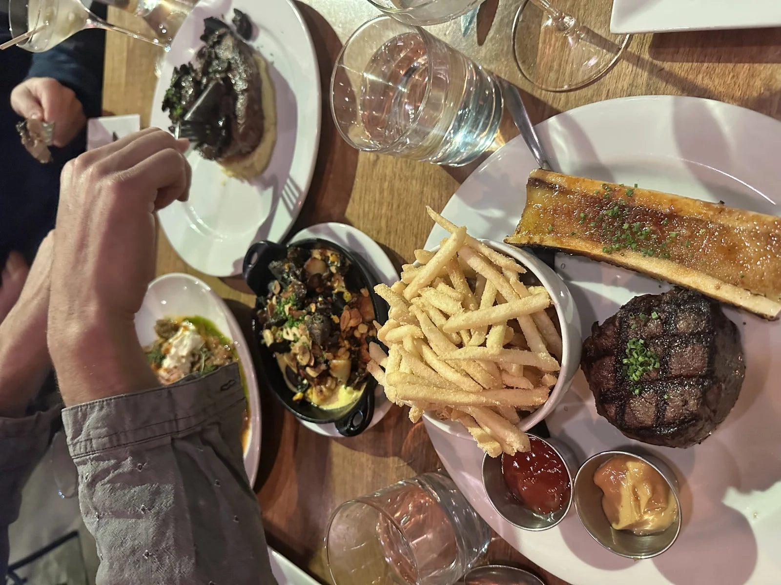 overhead spread: filet mignon on pink plate w/ side of roasted bone marrow, shoestring …