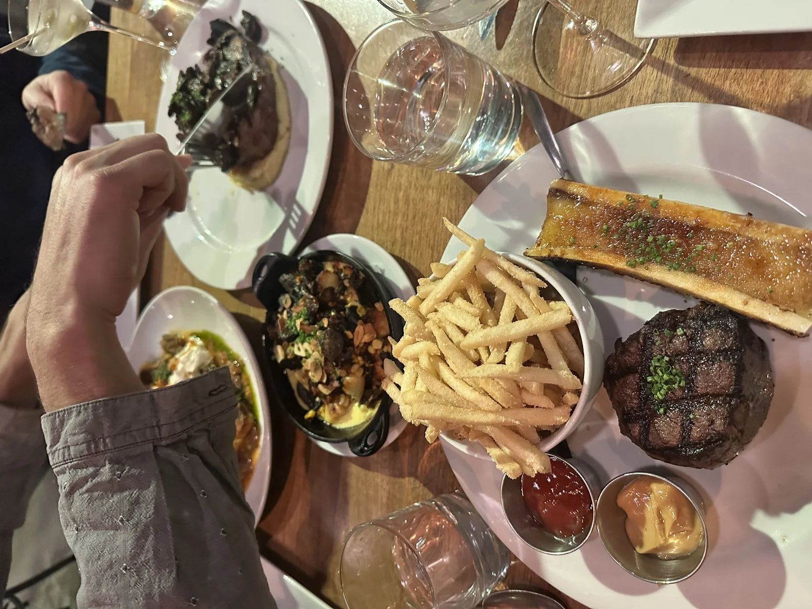 same overhead spread as prior, tighter framing: filet, bone marrow, fries, mushroom cas…