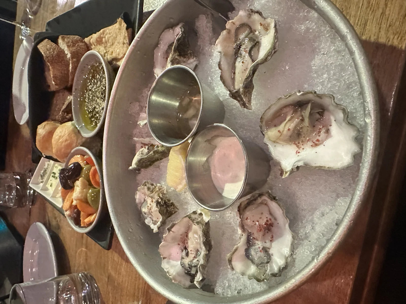 half-dozen raw oysters on a metal ice platter w/ mignonette + cocktail sauce, bread + o…