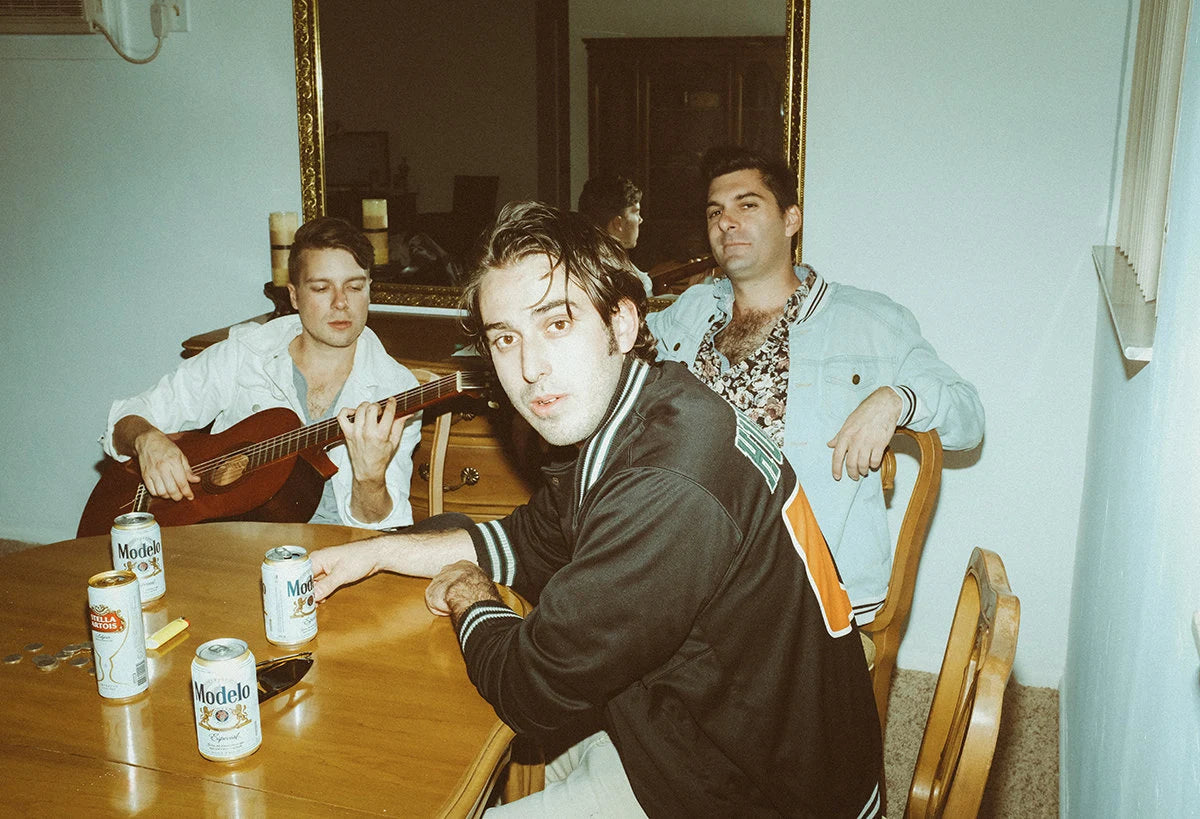 The band around a dining table with Modelos and an acoustic guitar